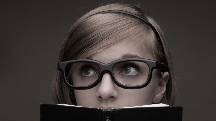 nerdy girl looking over a book